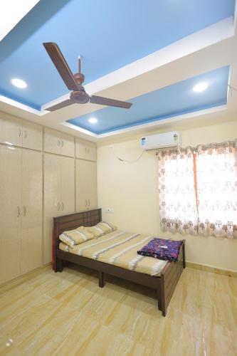 Cette chambre comprend un lit et un ventilateur de plafond. dans l'établissement Newly built spacious and luxurious 2bhk with scenic hill views in tirupati, à Tirupati