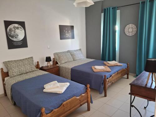 a bedroom with two beds with blue sheets and a window at Angel's apartments in Panayía