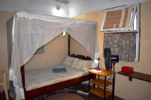 a small bed with a canopy in a room at Budget self-contained room on the GROUND FLOOR at JamboHouse Lamu in Lamu