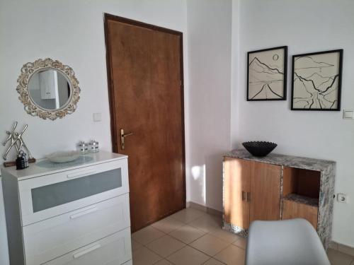 a bathroom with a wooden door and a mirror at Angel's apartments in Panayía
