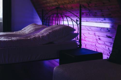 Cama en habitación con iluminación púrpura en Zöld Éden Kabin, en Makó