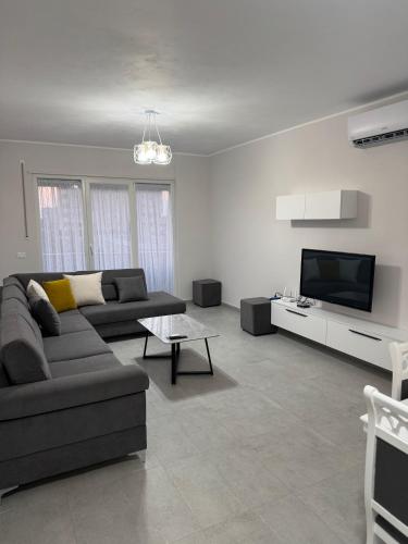 a living room with a couch and a flat screen tv at Gray & White Escape - Shkoder in Shkodër