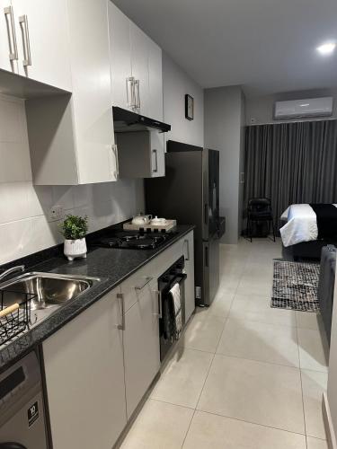 a kitchen with a sink and a stove top oven at The Fig Studio Apartment-A203 in Gaborone