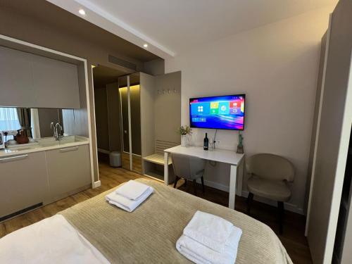 a bedroom with a bed and a desk and a tv on the wall at alliance pearl Batumi in Batumi