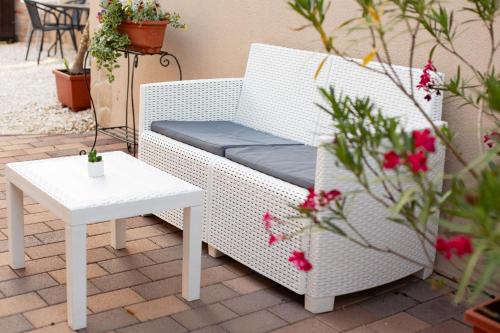 a white wicker chair and a table on a patio at R.Gold Apartman in Makó