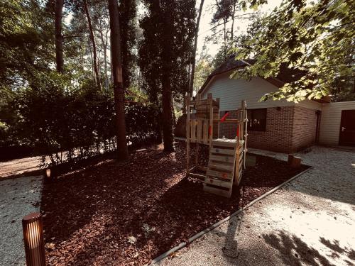a playground in a yard next to a house at Five Trees Forest Home in Lanaken