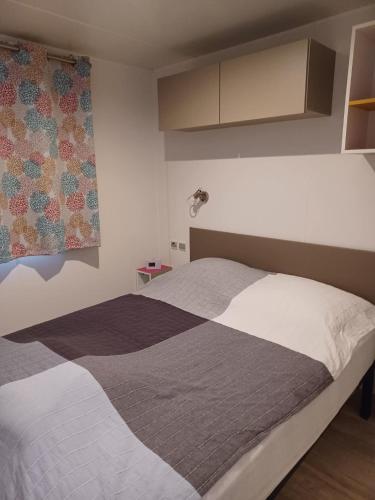 - une chambre dotée d'un lit avec une couverture grise et blanche dans l'établissement Mobil Home dans camping familial, à Vic-la-Gardiole