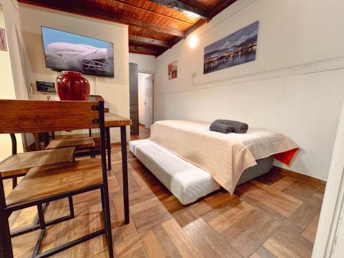 een slaapkamer met een bed, een tafel en een tv bij LA CASA DE FRIDA in Ushuaia