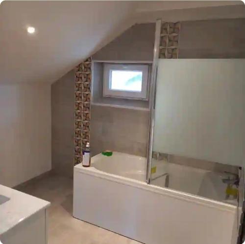 a bathroom with a bath tub and a window at Grande maison de bourg in Montpon-Ménestérol