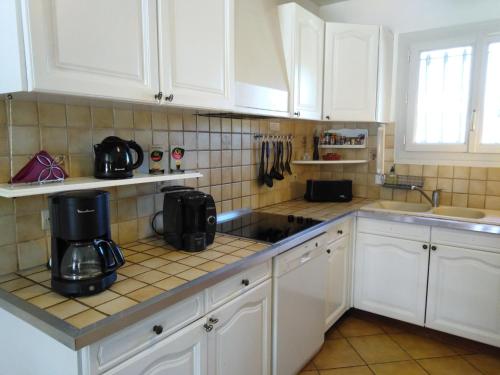 une cuisine avec des placards blancs et une cafetière sur le comptoir dans l'établissement Sud Cévennes - Maison avec piscine privée -, à Cazilhac