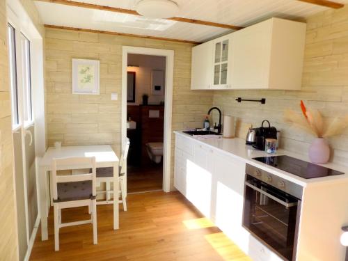 a kitchen with white cabinets and a table in it at Ostsee Tiny Haus Spatz in Barth