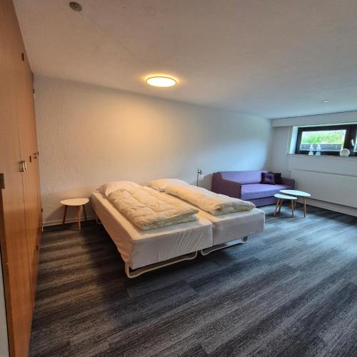 a bedroom with a bed and a purple couch at Studiolejlighed I Hvide Sande Centrum in Hvide Sande