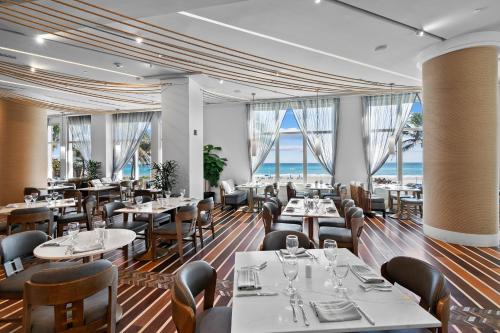 a restaurant with tables and chairs and a view of the ocean at Oceanfront Palm Beach Resort & Spa Singer Island in Riviera Beach