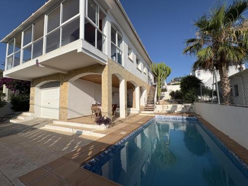 a house with a swimming pool in front of a building at Charming Catalan Villa with Pool & Views in Cunit