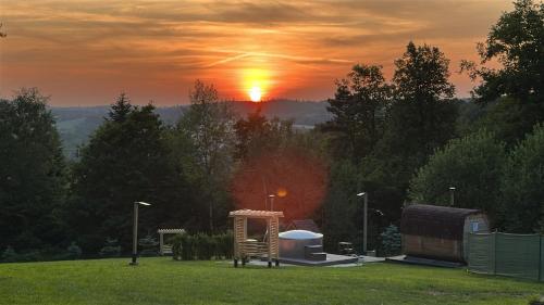 a sunset in a field with a gazebo at Oleksowiczówka in Zborowice