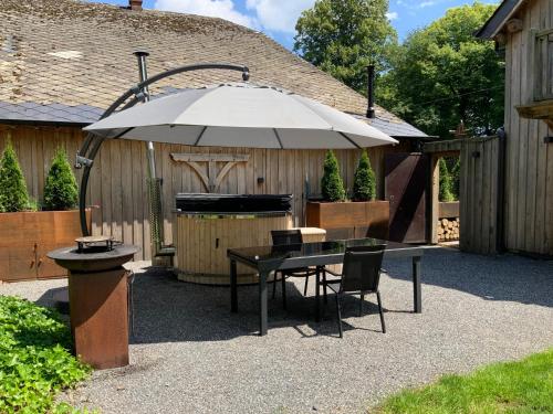 a patio with a table and an umbrella at Au Charme de Rachamps - 4 personnes in Bastogne