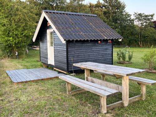 a black shed with a picnic table and a bench at Hyggelig hytte i landlig idyl in Sønderborg