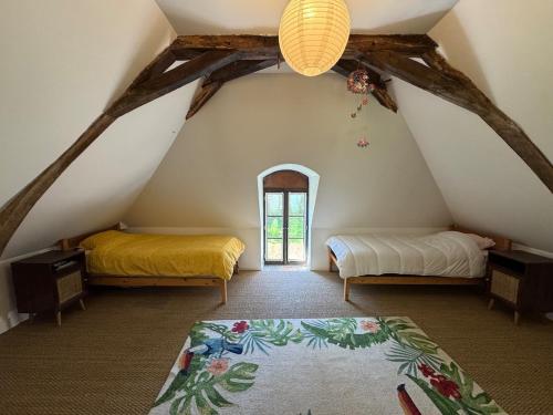 a attic room with two beds and a window at Charmant corps de ferme réhabilité en Mayenne in Daon
