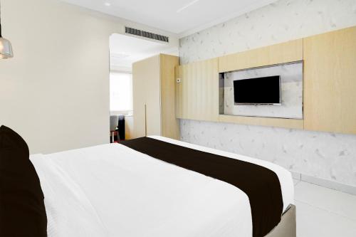 a bedroom with a bed and a tv on a wall at Super Townhouse Oak AECS Layout Brookfield in Bengaluru