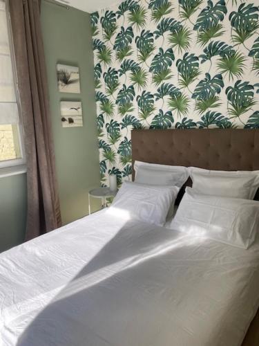 a bedroom with a white bed with a floral wall at Duplex 90 m2, Le Touquet, quartier Westminster 3 chambres, 6 couchages, 1 parking, Location à la semaine en juillet, août et pendant les semaines de vacances scolaires de fin d'année, sinon 2 nuits minimum in Le Touquet-Paris-Plage