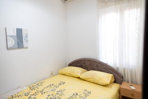 a bedroom with a bed with yellow sheets and a window at Villa Serenita in Ulcinj