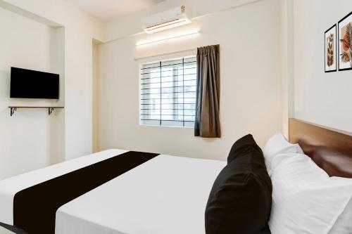 a bedroom with a bed and a window at Super Townhouse Hennur Prakruthi Layout Bangalore in Bengaluru
