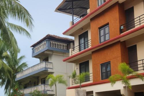 an apartment building with balconies and palm trees at XZ Apartment and Villa with kitchen GOA in Nagoa-Bardez