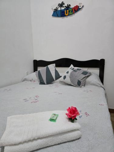 a bed with a rose sitting on top of it at Pousada Casa de Buzios in Búzios
