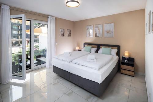 a bedroom with a large bed and a balcony at Blue Sky Flat, Apartment, 73qm, 4-6 Personen, Neubau Süd-Balkon mit Lounge-Möbeln, Schwarzwald-PLUS inkl 80 Gratis-Attraktionen täglich in Baiersbronn