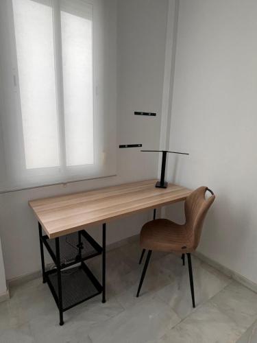 a wooden desk with a chair and two windows at Dúplex Los Arcos in Cabra