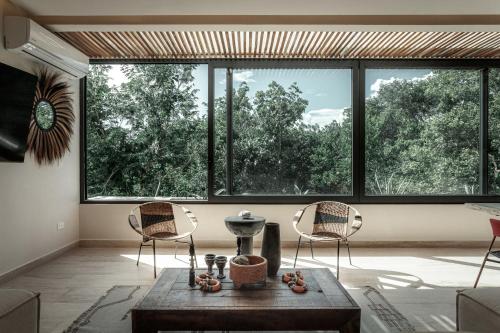 a living room with a table and chairs and a large window at Ka'ana Condo in Tulum