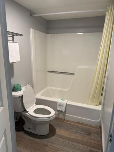 a white bathroom with a toilet and a bath tub at Riviera Motel in Kissimmee