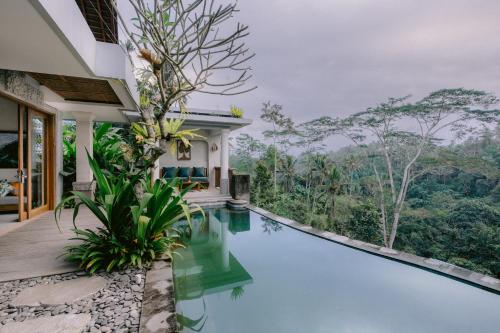 a swimming pool in a villa with a view of the forest at Sanggraloka Ubud in Ubud