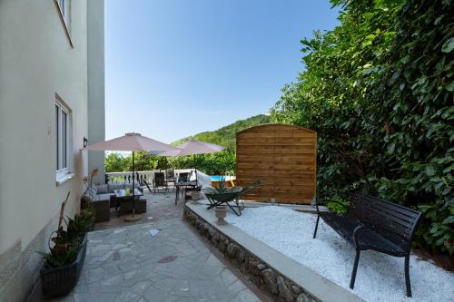 a patio with a bench and an umbrella at Apartments Villa DaMa in Volosko