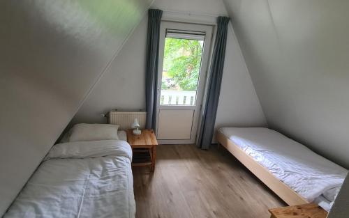 two beds in a small room with a window at Bosvilla in Harfsen