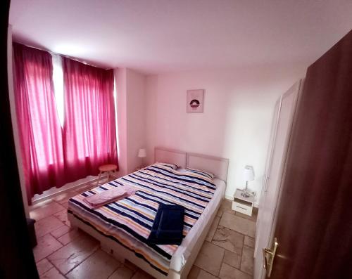 a bedroom with a bed and red curtains at Apartament Vallarta in Kavarna