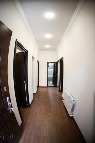 a hallway with white walls and wooden floors and a door at Maison spacieuse à Erevan in Aghk'ilisa