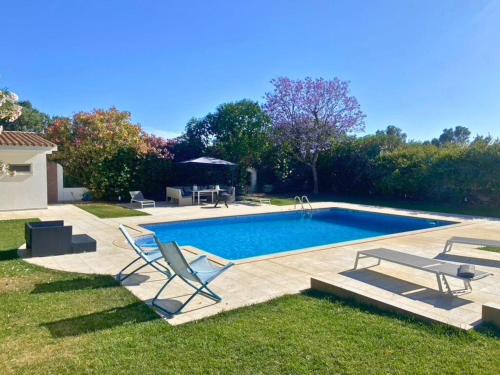 a swimming pool with two chairs and a table at Quinta Verde Algarve in Medronhal