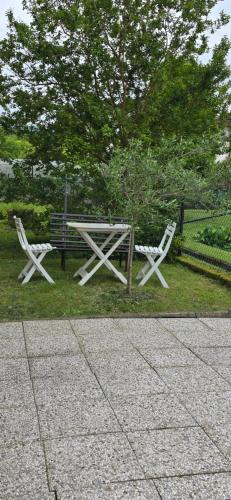 two white chairs and a picnic table in the grass at Confortevole Appartamento a Belluno in Belluno