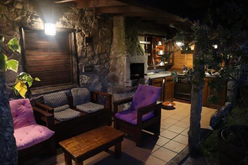 ein Wohnzimmer mit lila Stühlen und einem Steinkamin in der Unterkunft Casa de Penim in Paredes de Coura