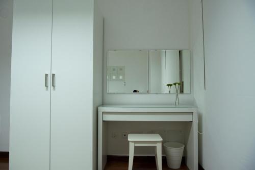 La salle de bains est pourvue d'un lavabo et d'un tabouret sous un miroir. dans l'établissement AL embaixador, à Alenquer