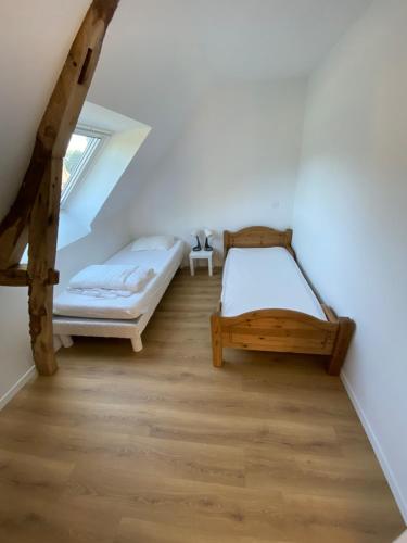 a attic bedroom with two beds and a window at La grange du clos in Angiens