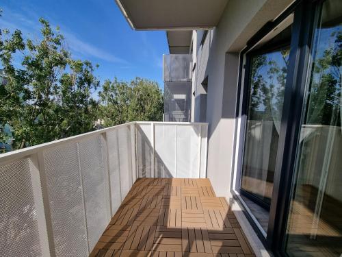 a balcony with a wooden floor and glass doors at Srebrna Ostoja 65- Atlas Arena, PIOTRKOWSKA, Manufaktura, PRYWATNY PARKING in Łódź
