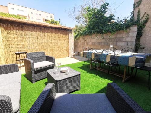 a patio with a table and chairs on grass at Le Cocon - Rénové I Clim I Terrasse I WIFI I Hypercentre in Miramas