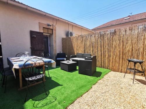 a patio with a table and chairs on grass at Le Cocon - Rénové I Clim I Terrasse I WIFI I Hypercentre in Miramas