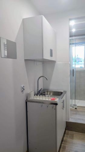 a white kitchen with a sink and a shower at Apartament Wysoka 580 z prywatną łazienką in Bielawa