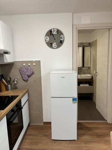 a white refrigerator in a kitchen with a clock on the wall at Soleneve in Passo del Tonale
