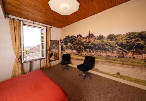 a bedroom with a bed and two chairs and a window at Jardin sur Loire in Blois