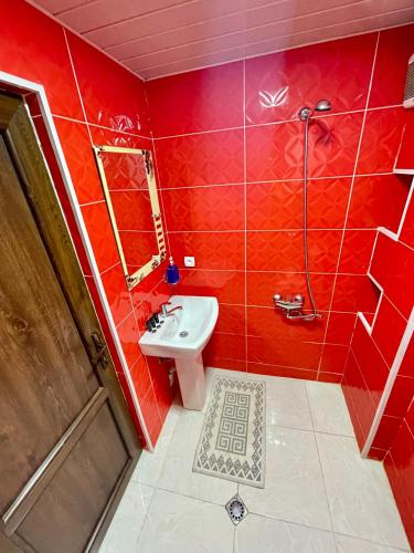 a red bathroom with a sink and a shower at Guest House Keti Margiani Mestia in Mestia