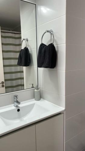 Un baño blanco con lavabo y espejo. en Depto Familiar Vista Mar 2D + Sofá Cama, en Antofagasta